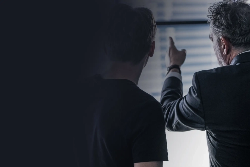 Mann zeigt auf Monitorwand im SOC